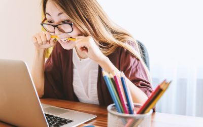 mulher mordendo lápis enquanto olha pro computador